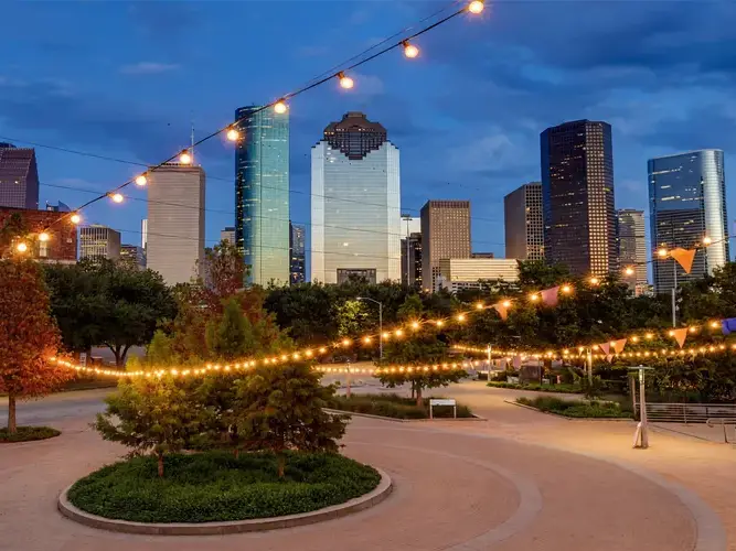 a city park with string lights and skyscrapers in the background
